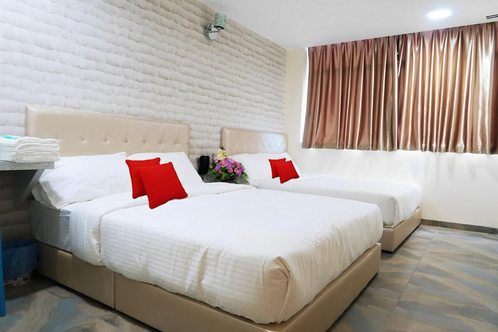 two beds in a hotel room with red pillows at Star Romantic in Batu Pahat