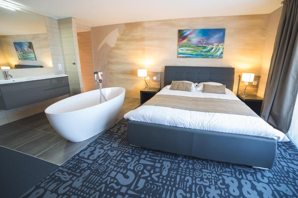 a bedroom with a large bed and a bath tub at Le Dormeur in Dorlisheim