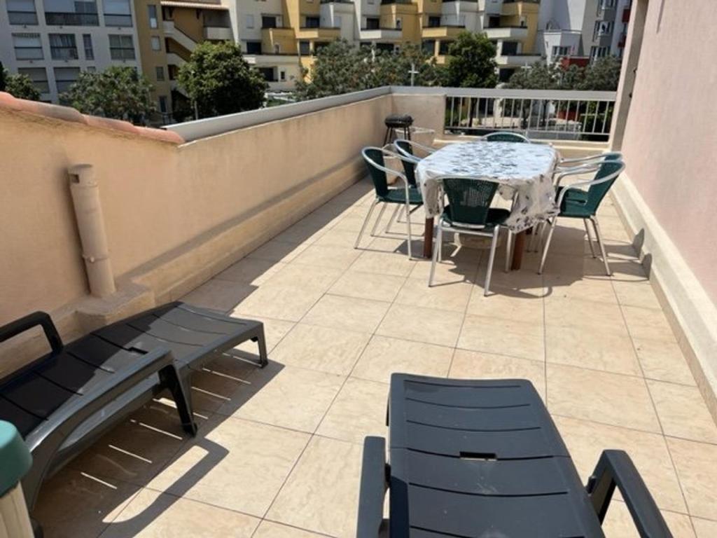 een patio met een tafel en stoelen op een balkon bij Appartement Cap d'Agde, 3 pièces, 6 personnes - FR-1-749-8 in Cap d'Agde