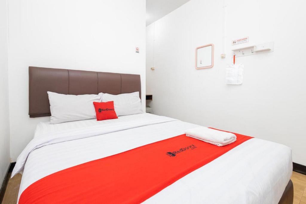 uma cama com um cobertor vermelho e branco em RedDoorz @ Tanjung Sari Surabaya em Tandjung-lor