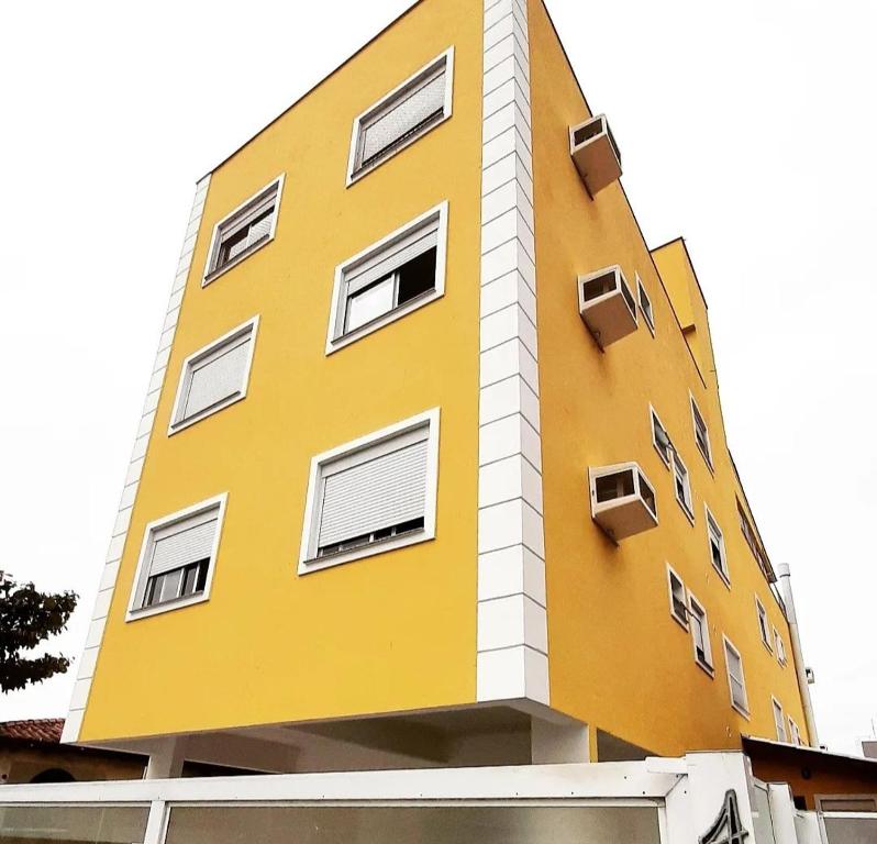 un edificio amarillo con ventanas laterales en Apartment Residencial Lídia Milani, en Florianópolis