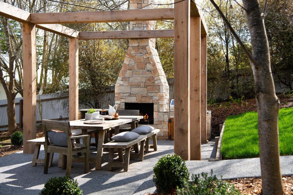 a patio with a table and a stone fireplace at Hambleden in Daylesford
