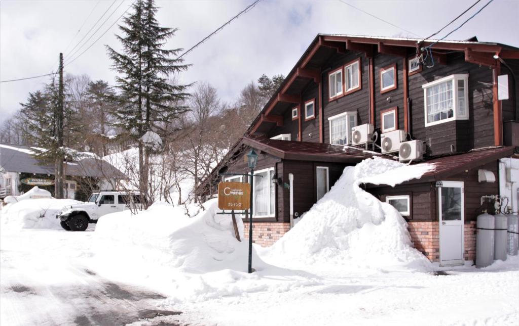 a house covered in snow with a sign in front at Urabandai Cranes in Kitashiobara
