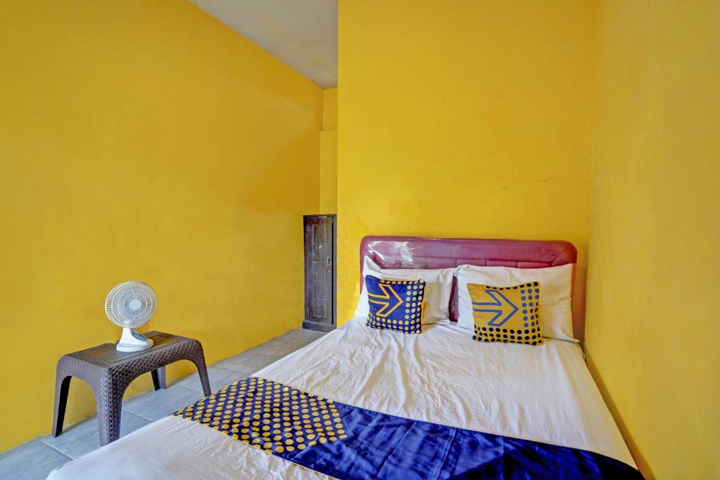 a yellow room with a bed and a night stand at SPOT ON 92827 Anisah Adil Homestay Syariah in Banyuwangi