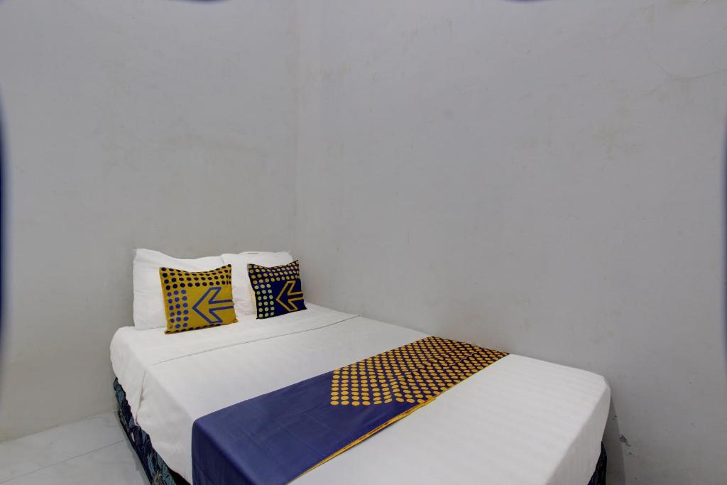 a bedroom with two beds with yellow and blue pillows at SPOT ON 92828 Galih Kost 1 Syariah in Grobogan