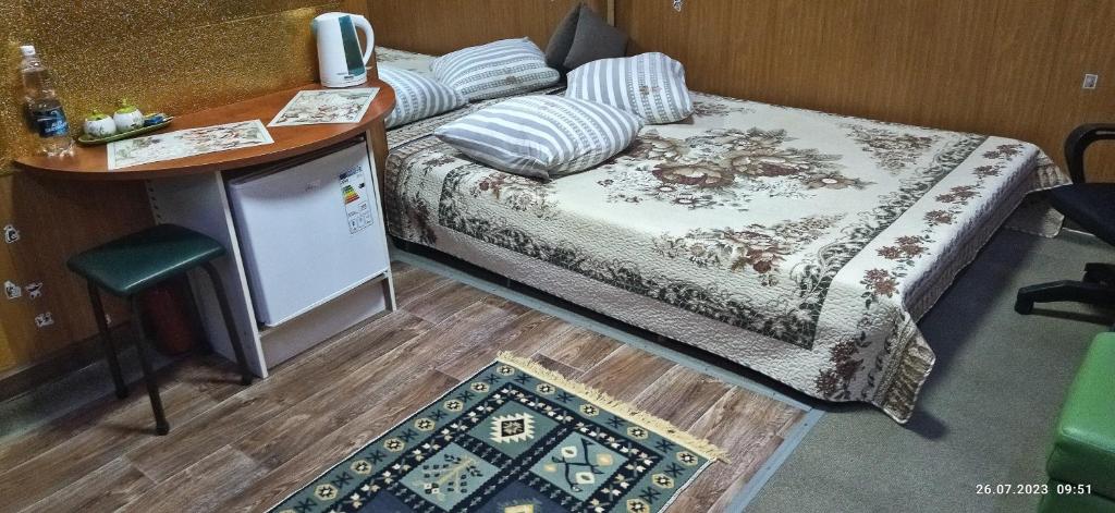 Habitación pequeña con cama, mesa y barra. en Apartment in a guest house, en Almaty