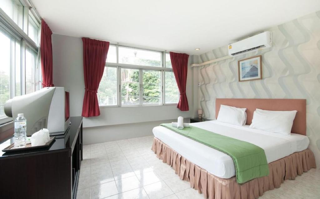 a bedroom with a large bed and a desk and window at FnB Hotel Central Pattaya in Pattaya