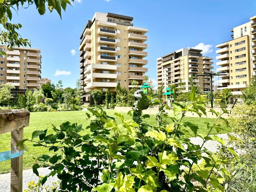 a green park with tall buildings in the background at Urban Plaza Astra - Rise Private Apartments & Suites in Braşov