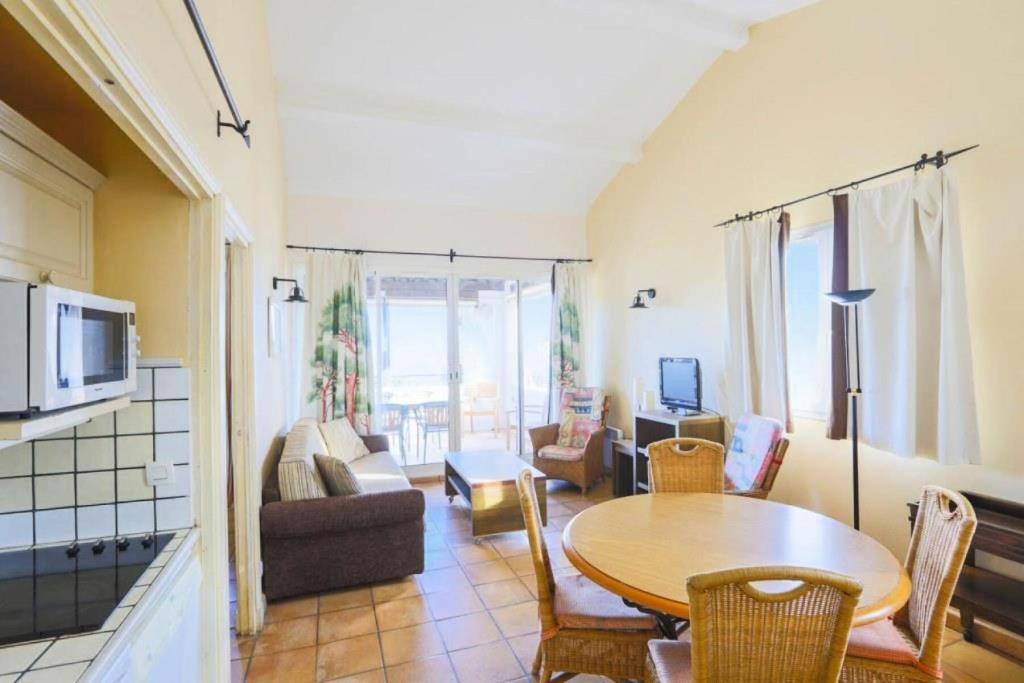 une cuisine et un salon avec une table et des chaises dans l'établissement Les Bastides aux Restanques du Golfe de St Tropez - maeva Home - Bastide pour 6 personnes belle vue sur la Baie MAE-7833, à Grimaud
