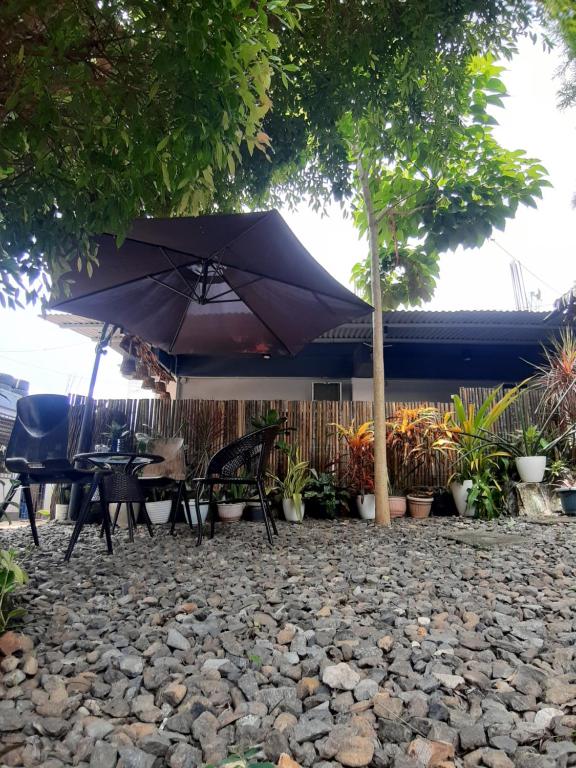 a patio with a table and an umbrella on a rock at Elisha's Guest House in Coron