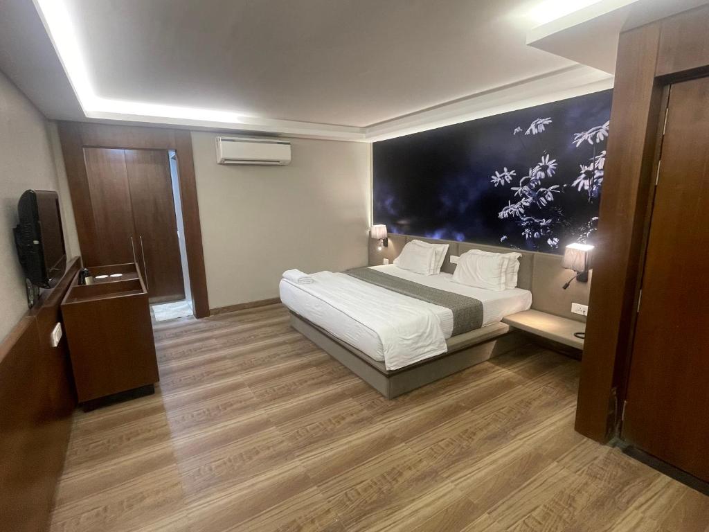 a hotel room with a bed and a large painting on the wall at LCH Fitness in Indore