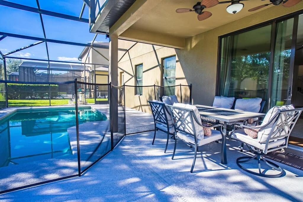 a patio with a table and chairs next to a swimming pool at 5 Bd Villa Home Theater Private Pool Game Room in Davenport