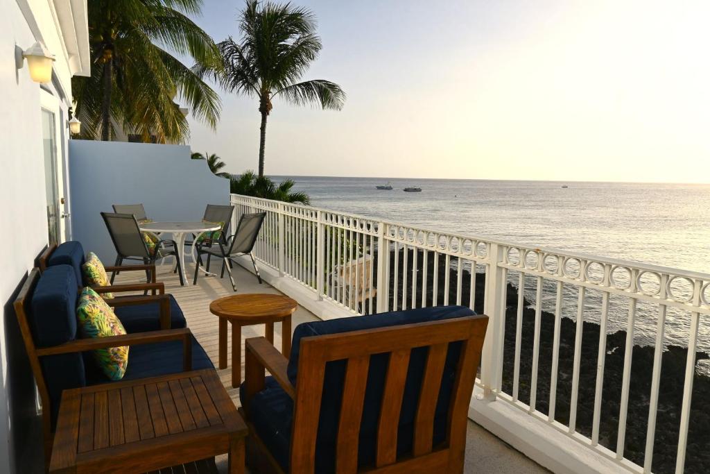 Un balcón con sillas, una mesa y el océano en Dive into Sunsets at The Residences, en George Town