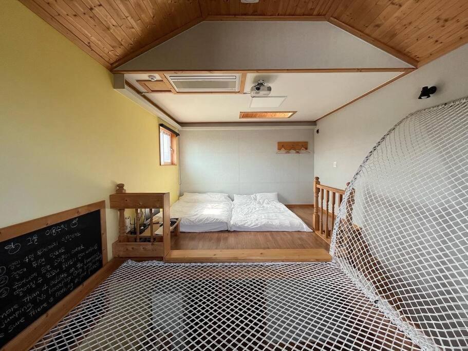 a small room with a bed and a net in it at Taeheung Art Theater Pension in Seogwipo