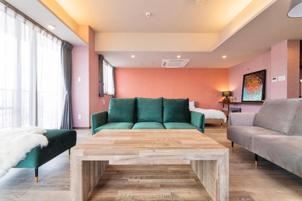 sala de estar con sofá verde y mesa en Breaky Hotel 中長期滞在向けのラグジュアリーモーテル空間 無料駐車場有, en Chatan