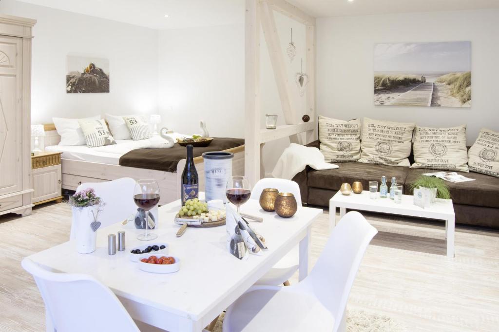 ein weißes Wohnzimmer mit einem Tisch und Weingläsern in der Unterkunft Schwalbennest in Flensburg