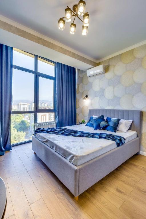 ein Schlafzimmer mit einem großen Bett und einem großen Fenster in der Unterkunft Asaapart Lamiya 2-72А in Almaty