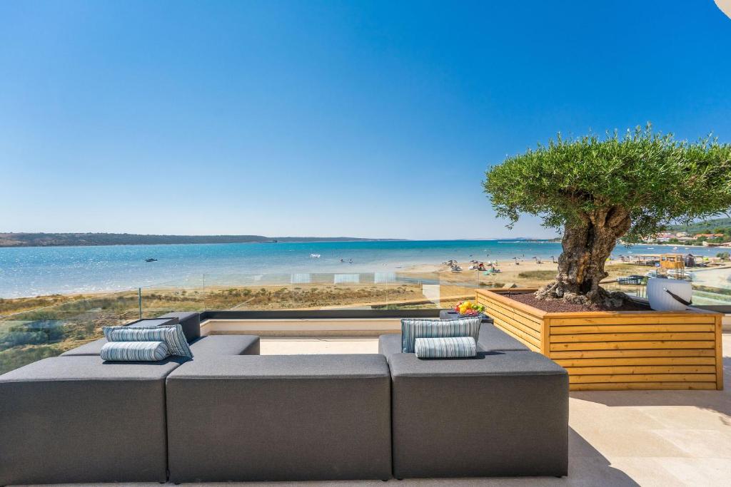 uma vista para uma praia com um sofá e uma árvore em Ljubac Seaside em Ražanac