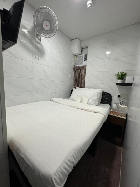 Mandarin Guest House في هونغ كونغ: غرفة صغيرة بها سرير أبيض ومروحة
