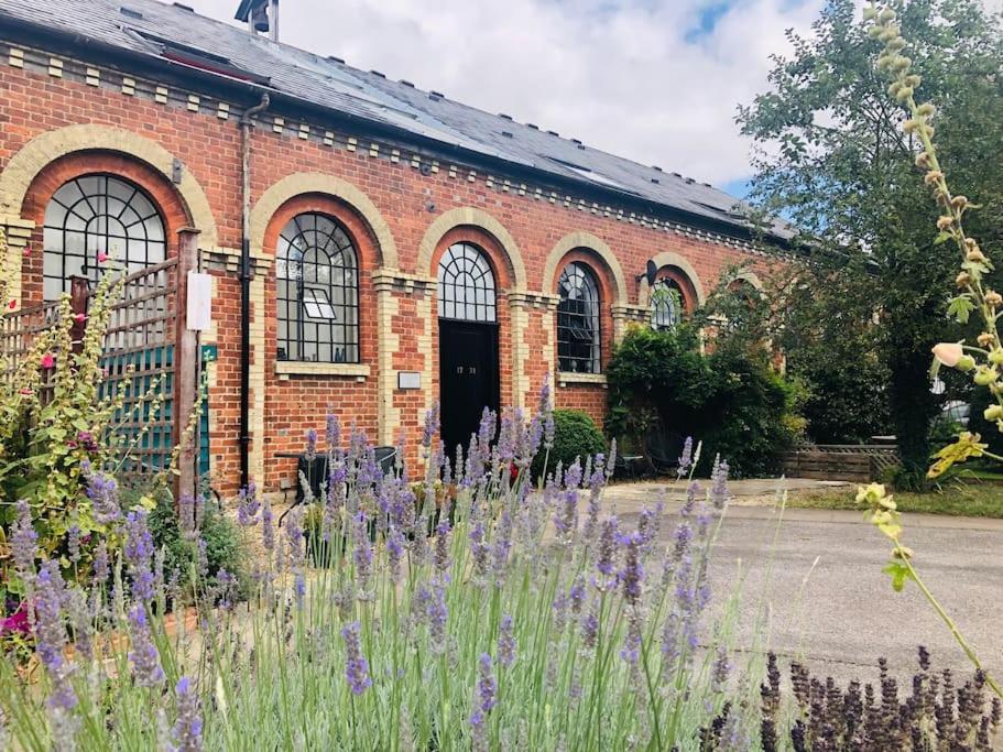 a brick building with purple flowers in front of it at The Old Foundry Wallingford Apartment & Parking in Wallingford