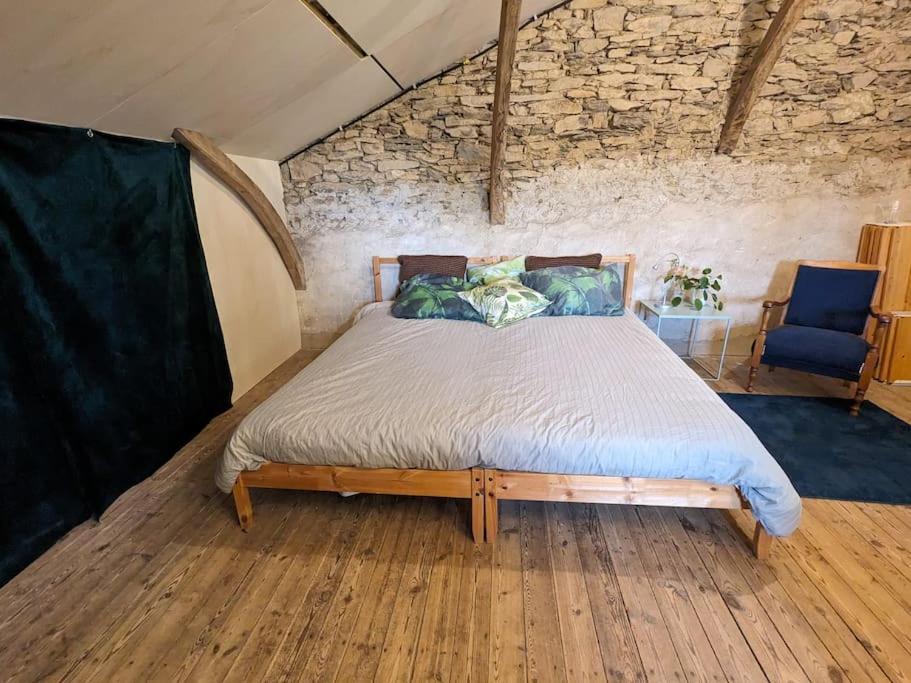 1 dormitorio con cama y pared de piedra en Relax in the Haute Vienne. en Séreilhac