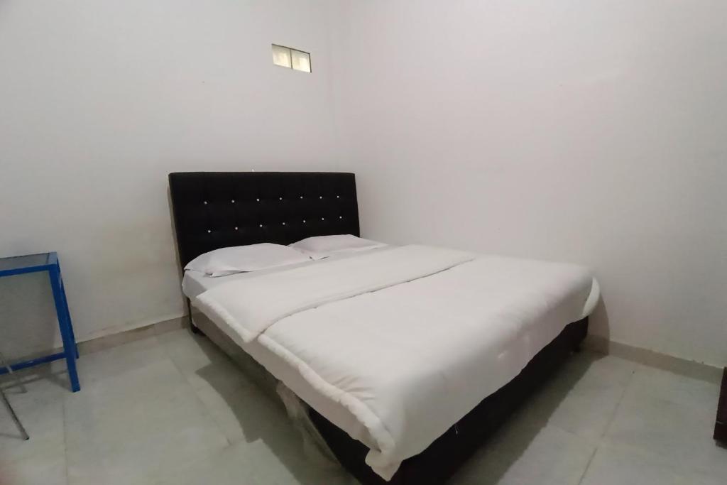 een bed met witte lakens en kussens in een kamer bij OYO 92833 Penginapan Syariah in Pekanbaru