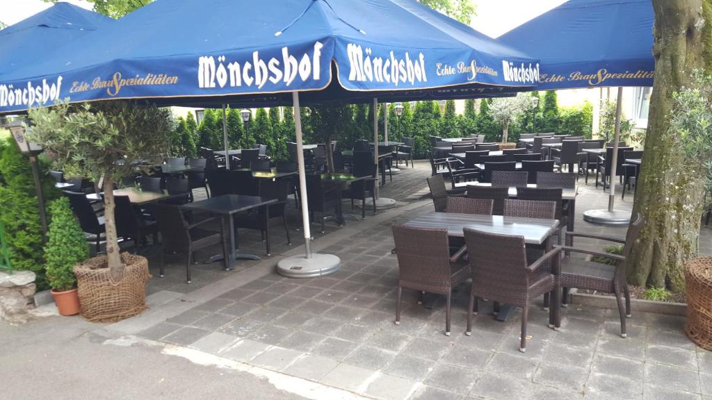 a restaurant with tables and chairs under a blue umbrella at Hotel Restaurant Platamon in Feuchtwangen