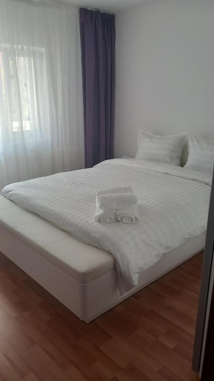ein weißes Bett mit weißer Bettwäsche und Kissen darauf in der Unterkunft Apartament Brasov in Braşov