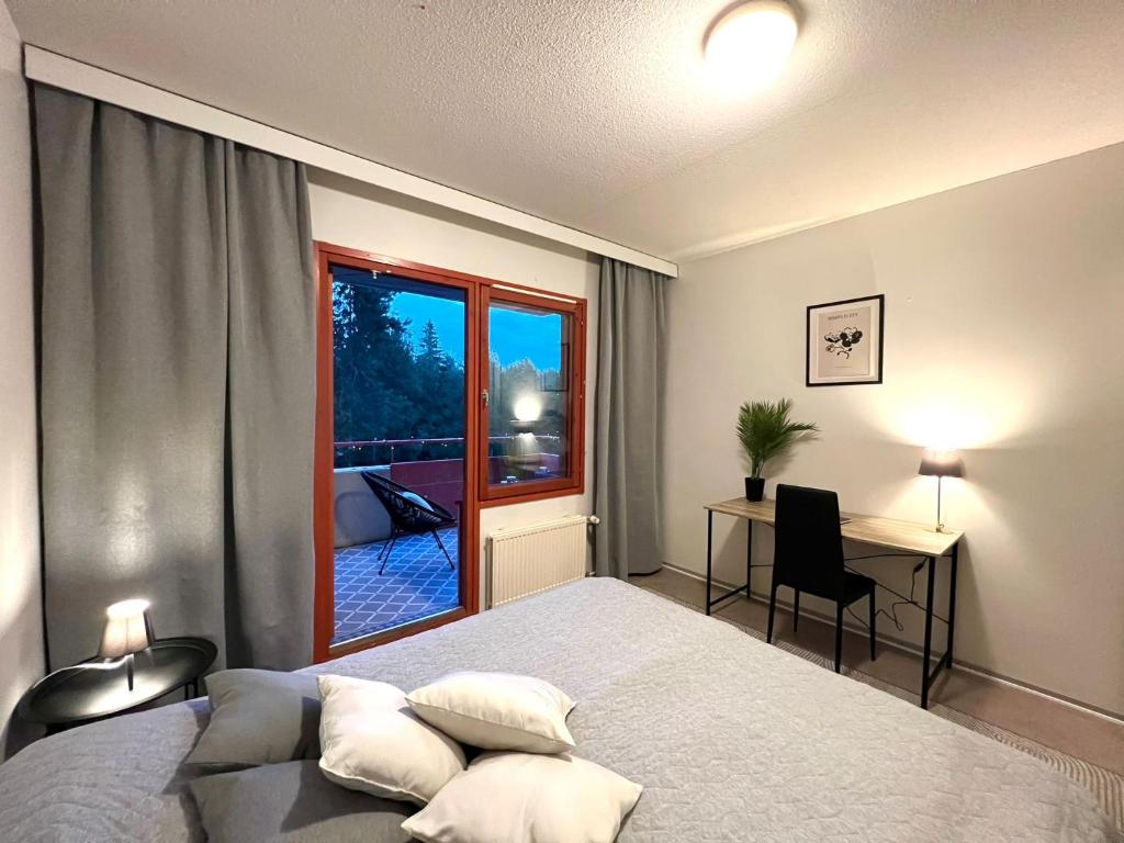 um quarto com uma cama, uma secretária e uma janela em Pearl of Helokka em Jyväskylä