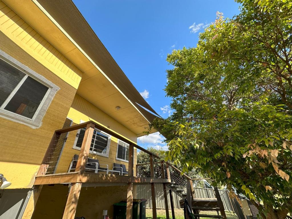 una casa amarilla con terraza y árbol en 2 Bedroom Apartment near Graftons Waterfront, en Grafton