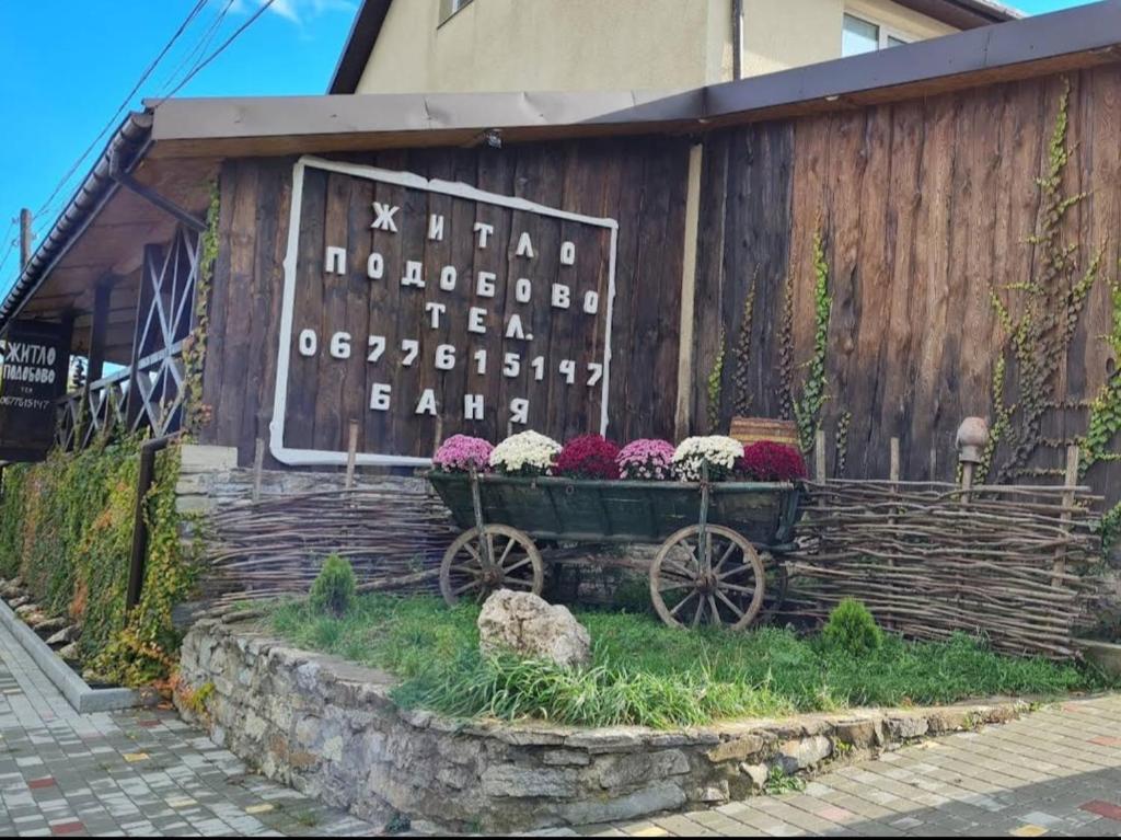 um edifício de madeira com um carrinho com flores em О.ФІС em Kamianets-Podilskyi
