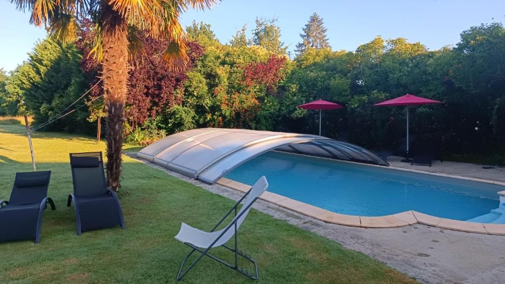 una piscina con sedie e ombrelloni in un cortile di Relais de la tour a Termes-dʼArmagnac