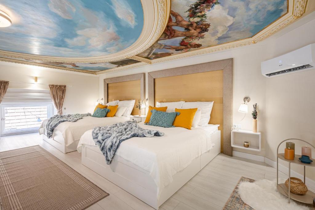 Szent István Apartments في بودابست: سريرين في غرفة نوم مع لوحة على السقف