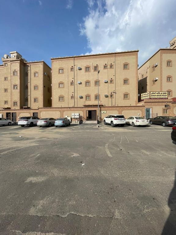 a parking lot with cars parked in front of a large building at شقق بن طالب in Khamis Mushayt