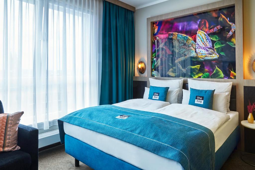 um quarto com uma cama azul e branca e uma janela em the niu Fusion em Hamburgo