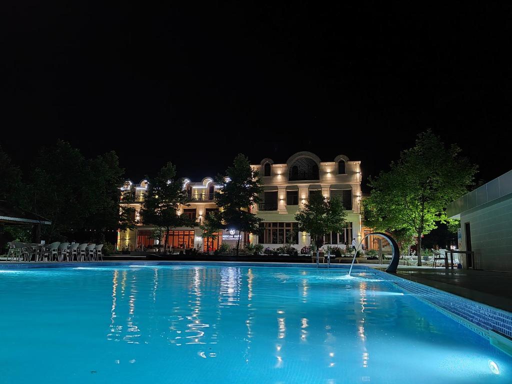 a large swimming pool in front of a building at night at Hirkan Park Hotel in Lankaran