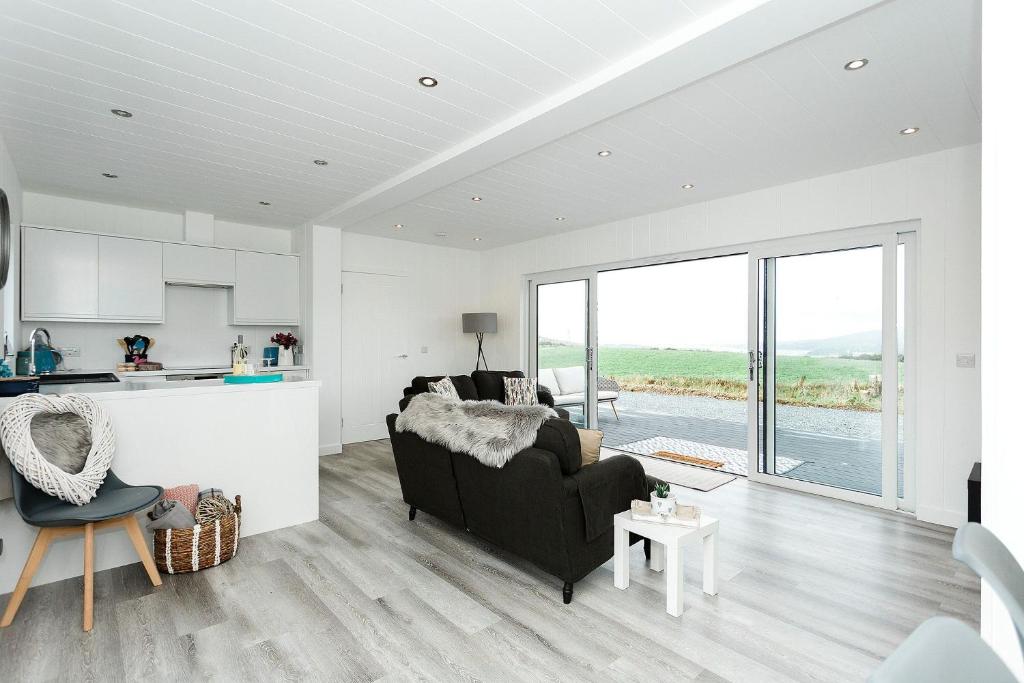 a living room with a couch and a kitchen at Sea Glass Lodge in Gatehouse of Fleet