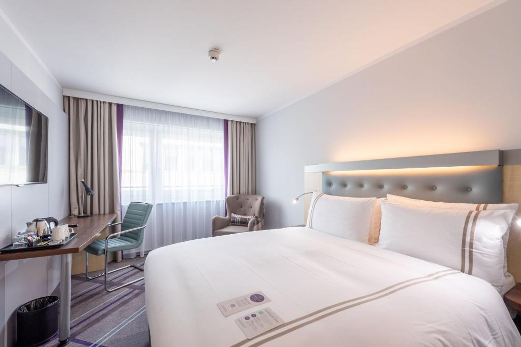 ein Hotelzimmer mit einem großen Bett und einem Schreibtisch in der Unterkunft Premier Inn Stuttgart Airport in Leinfelden-Echterdingen