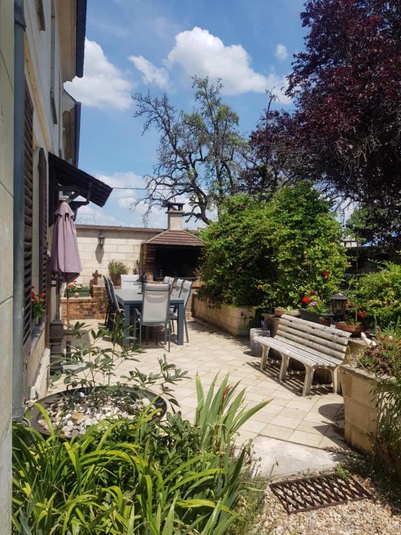 d'une terrasse avec une table, des chaises et un banc. dans l'établissement Au Grand Sapin Chambres chez l'habitant, à Hénonville