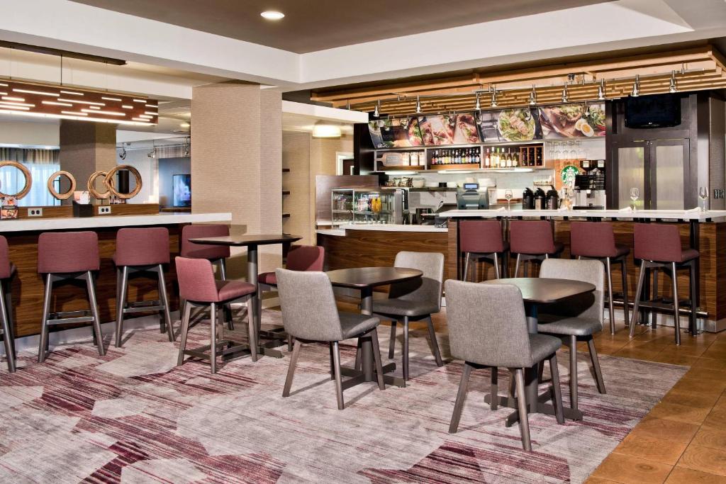 a restaurant with tables and chairs and a bar at Courtyard by Marriott Charlotte Ballantyne in Charlotte