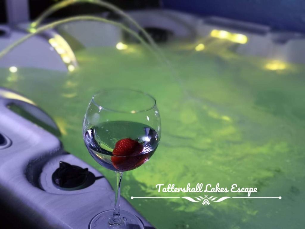 a wine glass with a strawberry in it next to a swimming pool at Meridian Tattershall Lakes Escape - Lakeside lodge caravan with a fishing peg LUXURY HOT TUB in Tattershall