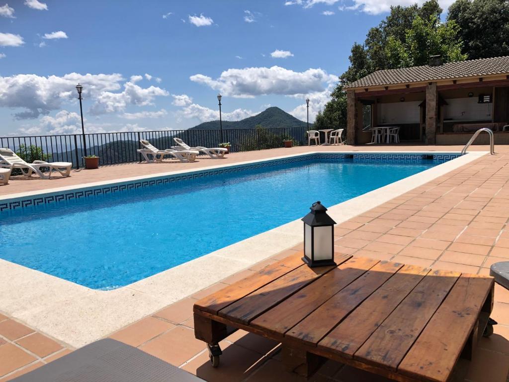 a swimming pool with a wooden bench next to it at Casa de muntanya Can Coll de Susqueda Girona in Susqueda