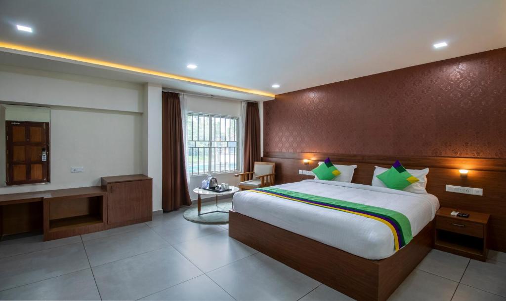 a hotel room with a large bed and a desk at Treebo Trend Chembra Residency in Kalpetta