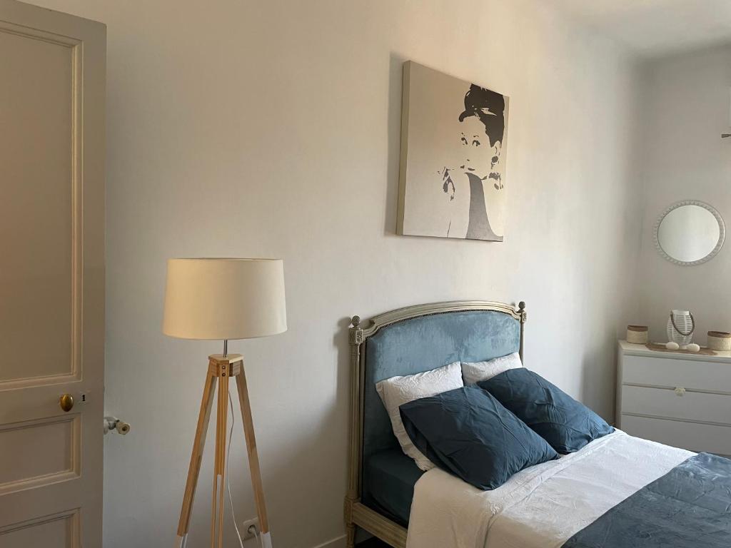 a bedroom with a bed with a blue headboard and a lamp at Spacieux T3 haussmannien in Toulon