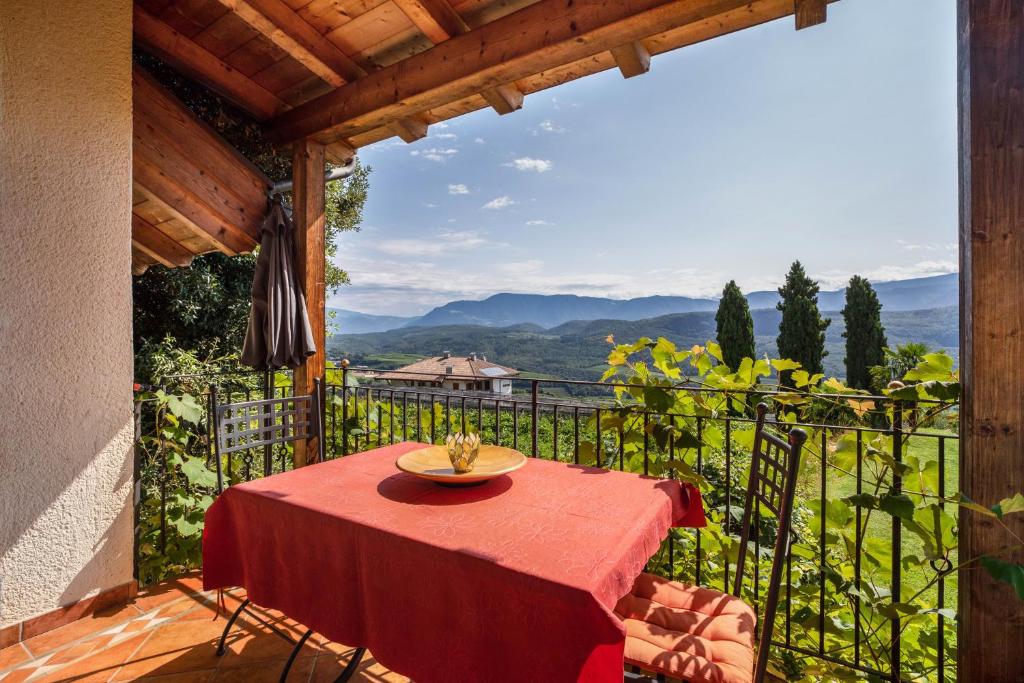 a table with a red table cloth on a balcony at Weingut Lieselehof Apt Rosengarten in Caldaro