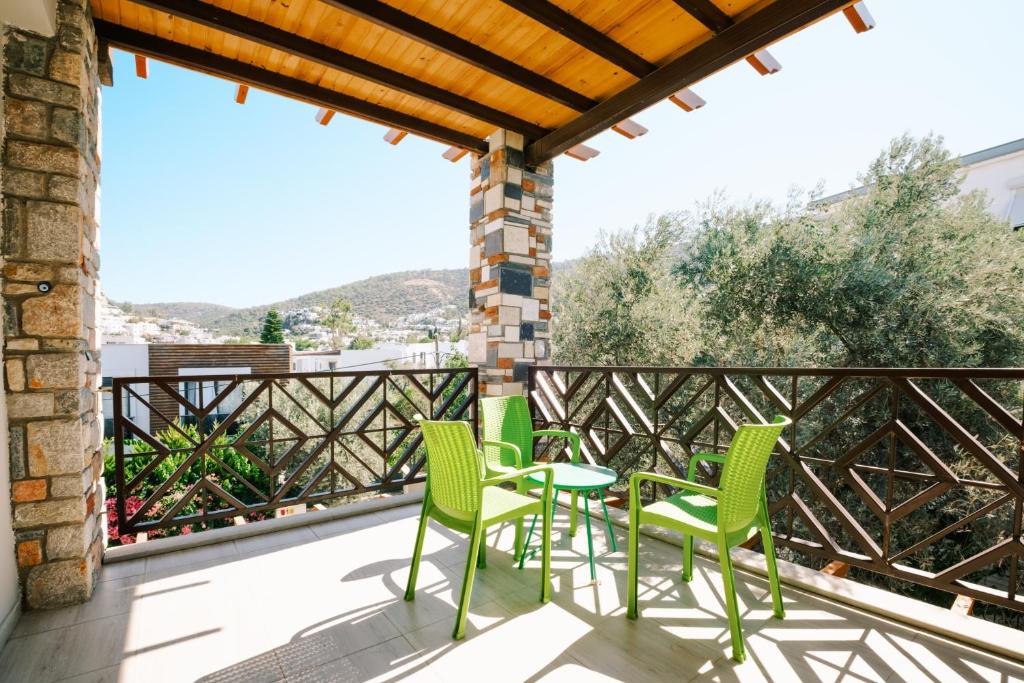 a patio with green chairs and a table on a balcony at Chic Flat w Balcony 3 min to Beach in Bodrum in Bodrum City