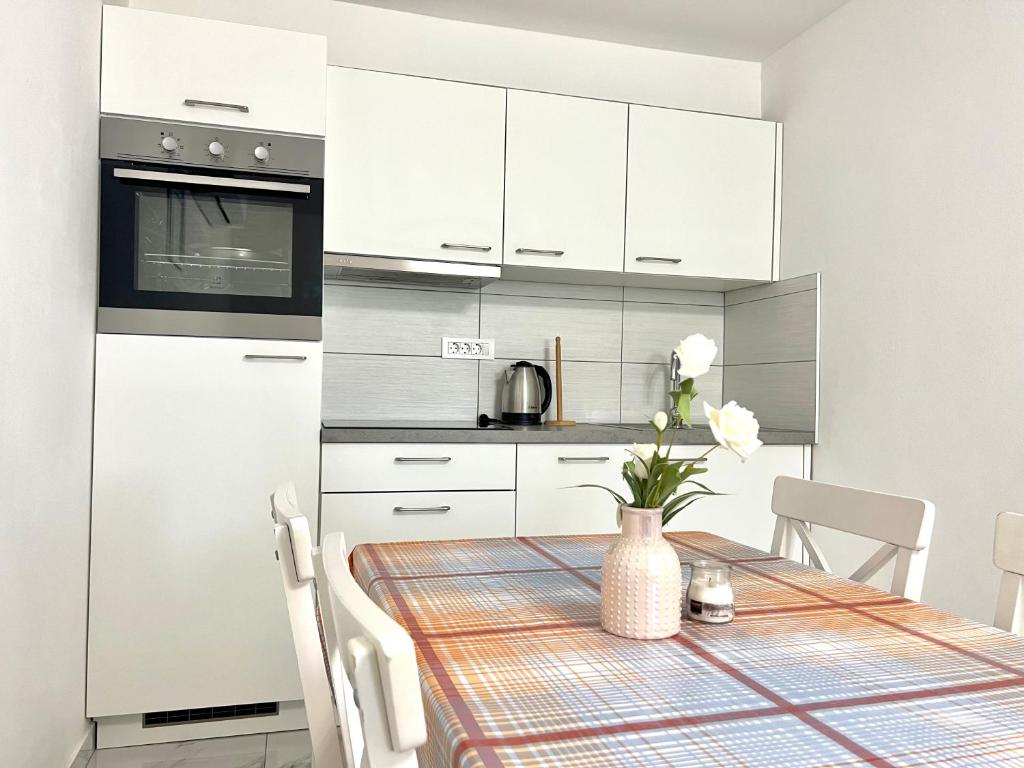 a kitchen with white cabinets and a table with a vase of flowers at ZARA APARTMENTS in Koper