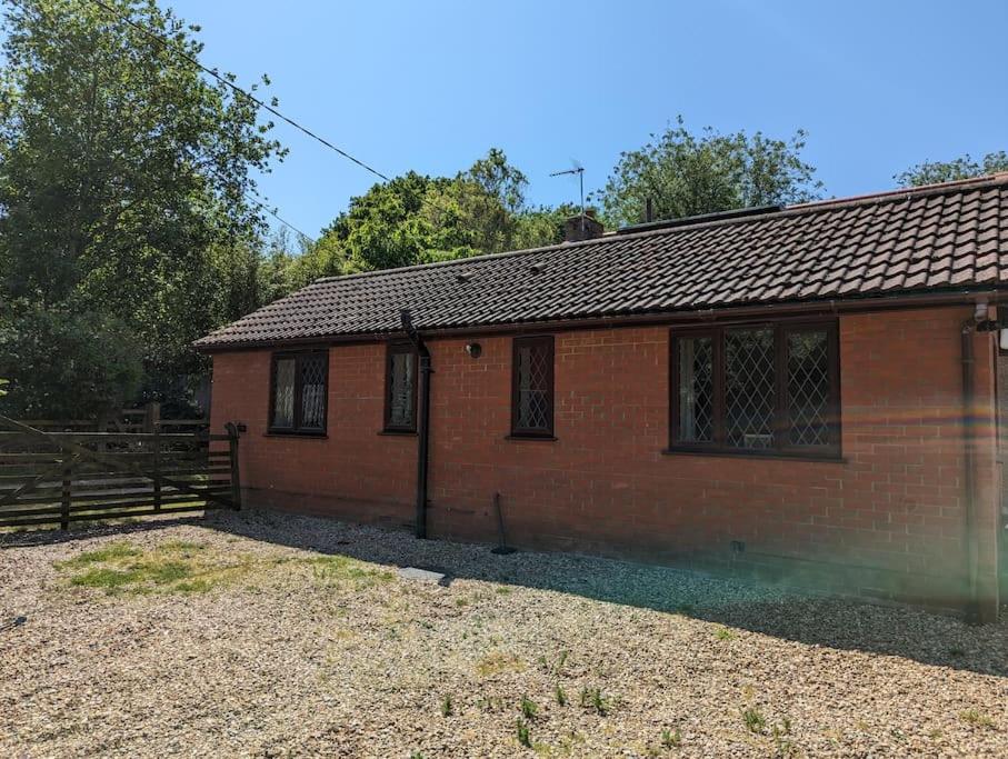 a red brick building with a fence next to it at Self-catering guest annex in Norwich