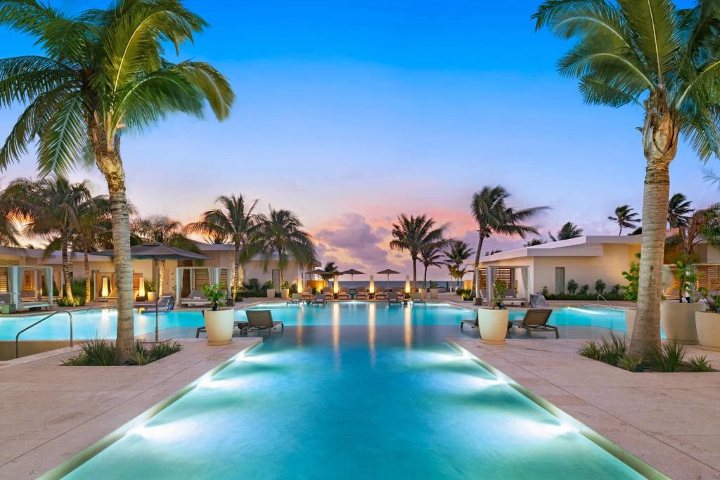 a swimming pool with palm trees in a resort at Alaia Belize, Autograph Collection in San Pedro