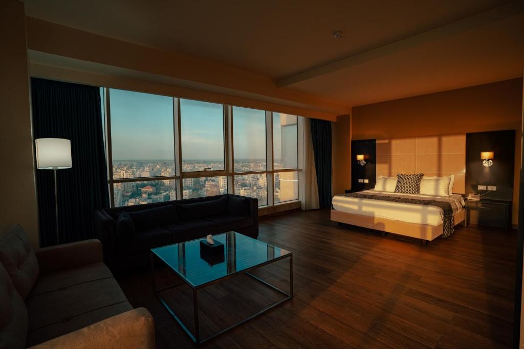 a bedroom with a bed and a couch and a glass table at Carmel Hotel in Ramallah